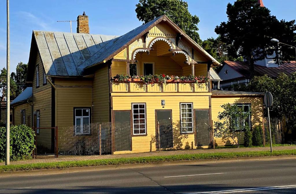 a yellow house with a balcony with flowers on it at Sunrise Apartments in Jūrmala
