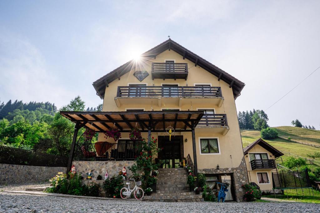 a large house with a porch and stairs in front of it at Sapphire Chalet - Moieciu de sus in Moieciu de Sus