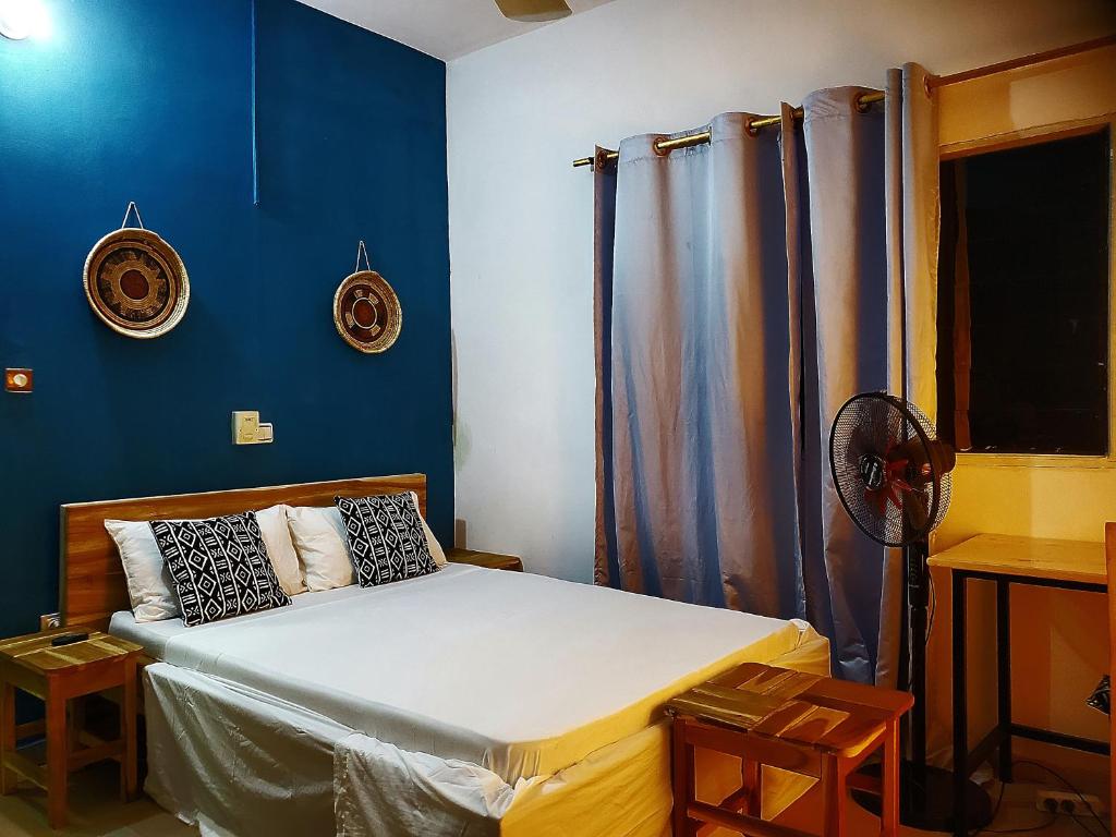 a bedroom with a bed with blue walls at Au cœur de Ouidah in Ouidah