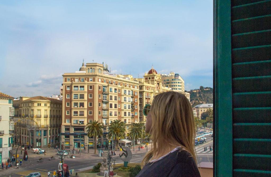 Une femme qui regarde par une fenêtre dans une ville dans l'établissement Venecia, à Malaga