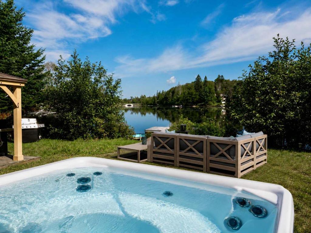 a jacuzzi tub with a view of a lake at Le Lac Apaisant - Rustic Haven by the Water in Saint-Calixte
