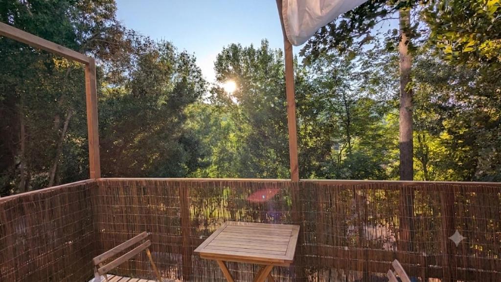 a wooden table and two chairs on a balcony at Entre Bois & Cévennes in Anduze