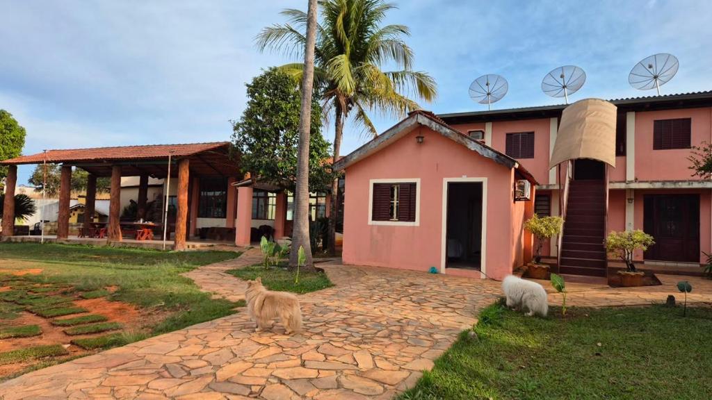 a house with three cats standing in front of it at Pousada Villa Cerrado in Caldas Novas