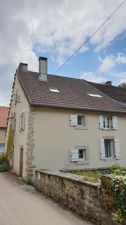 a white house with a stone wall next to it at Gîte La Salamandre in Passenans