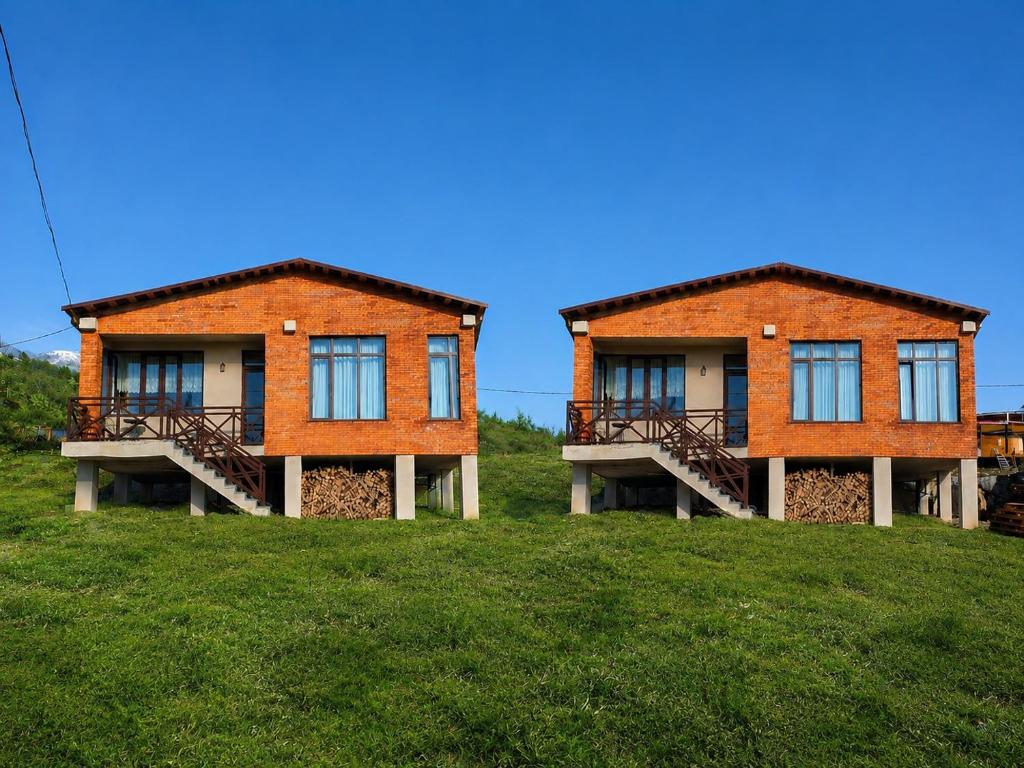 two buildings on top of a grassy hill at Datvina Panorama Chalets Mravaldzali, Racha in Oni