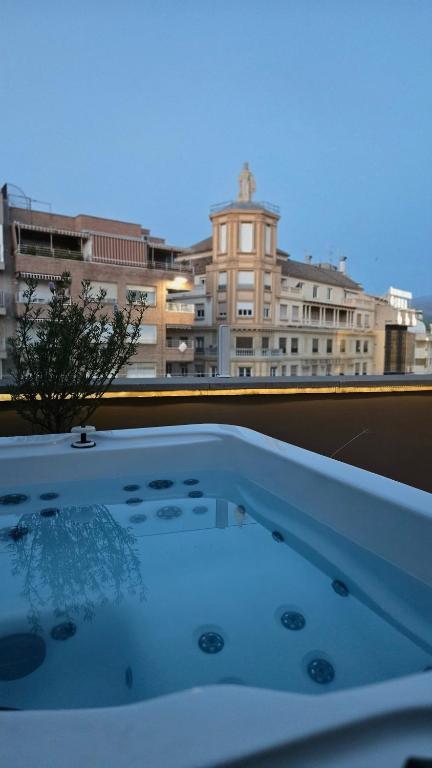 a hot tub on a balcony with a view of a city at RYAP Puerta Real in Granada