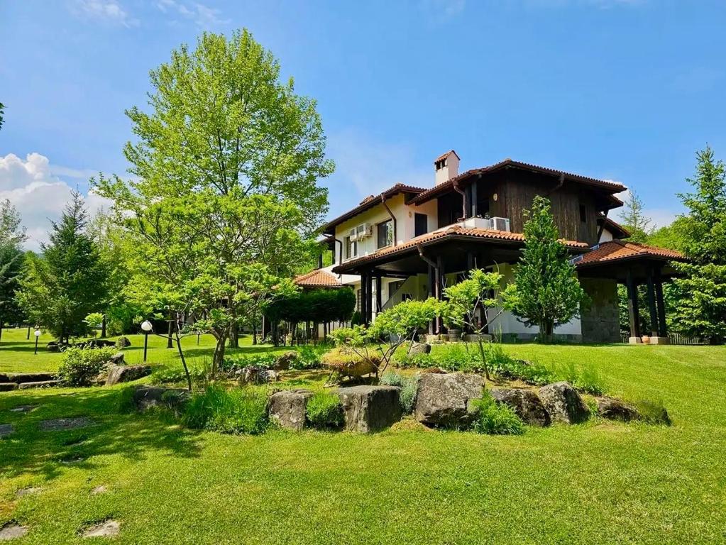 a house on a green field with trees and grass at Villa Foresta in Oreshak