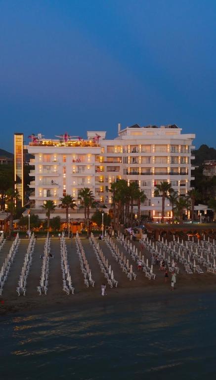 a large white building with a fountain in front of a beach at Klajdi Resort & SPA in Golem