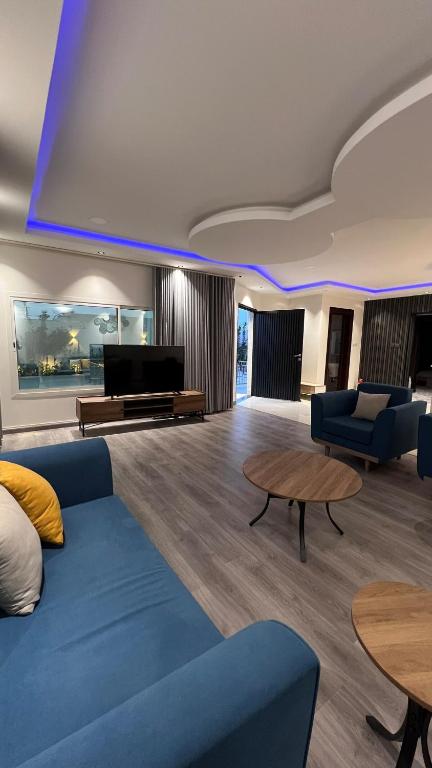 a living room with a blue couch and a tv at شالية بمسبح وجلسة خارجية- غرفتين نوم وملحق خارجي ومدخل سيارة in Unayzah