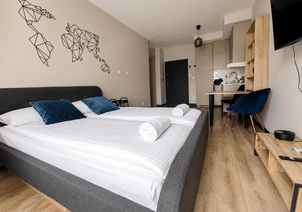 a bedroom with a large bed with white sheets and blue pillows at CudNajem Old Town Apartments - Bulvar in Elblag