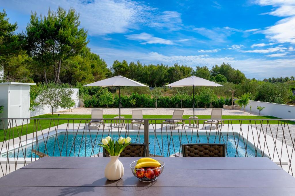 a table with a bowl of fruit on it next to a pool at Villa Rocco in Srima