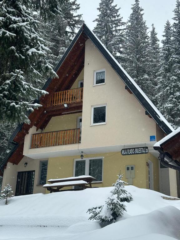 a building with a balcony in the snow at Vikendica Anja in Vlasic