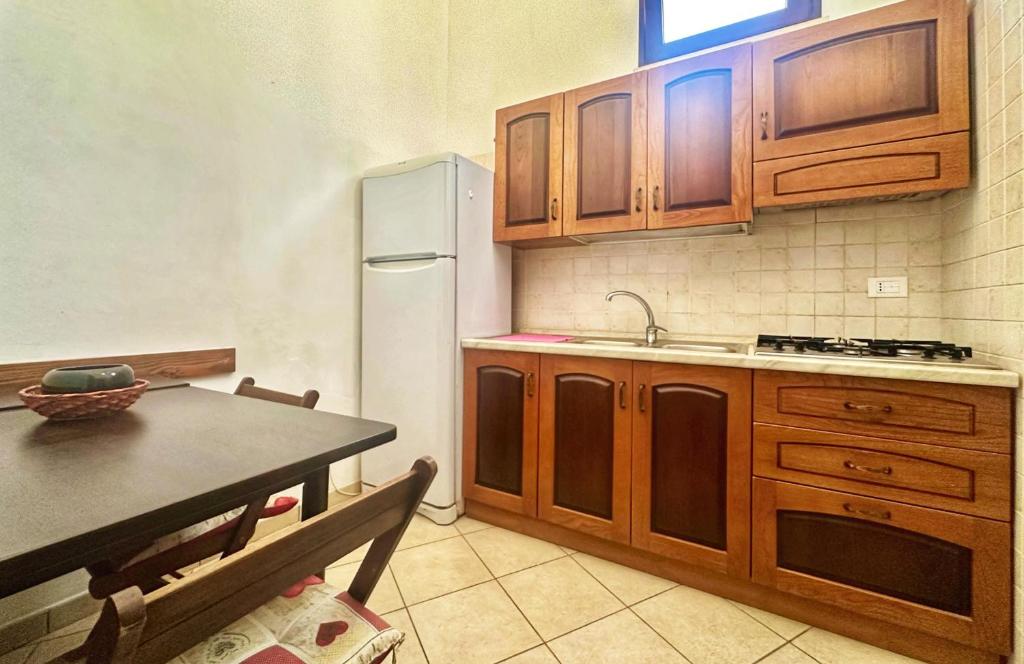 a kitchen with wooden cabinets and a table and a refrigerator at Stanze Appartamento ROSINA casa vacanze Cannole sulla via Francigena in Cannole