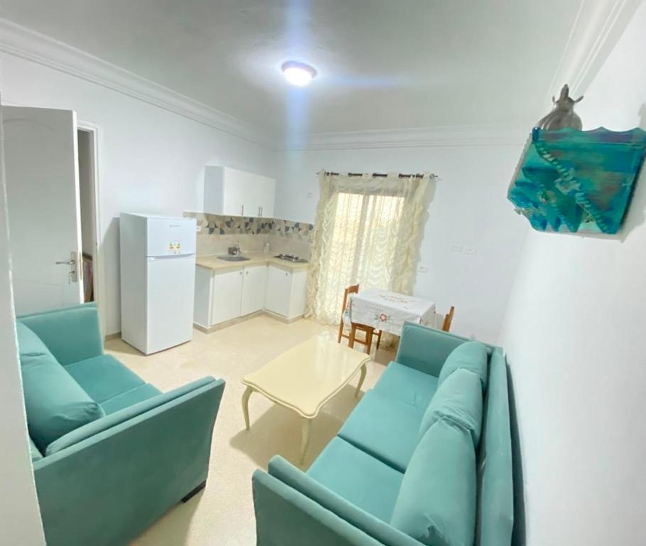 a living room with two blue couches and a kitchen at Soltane Résidence in Hammamet