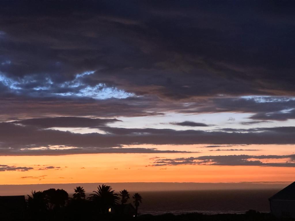 a sunset over the ocean with palm trees in the foreground at Happy Place in Grotto Bay
