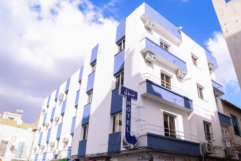 a white building with a blue sign on it at Hotel Métropole Résidence in Tunis