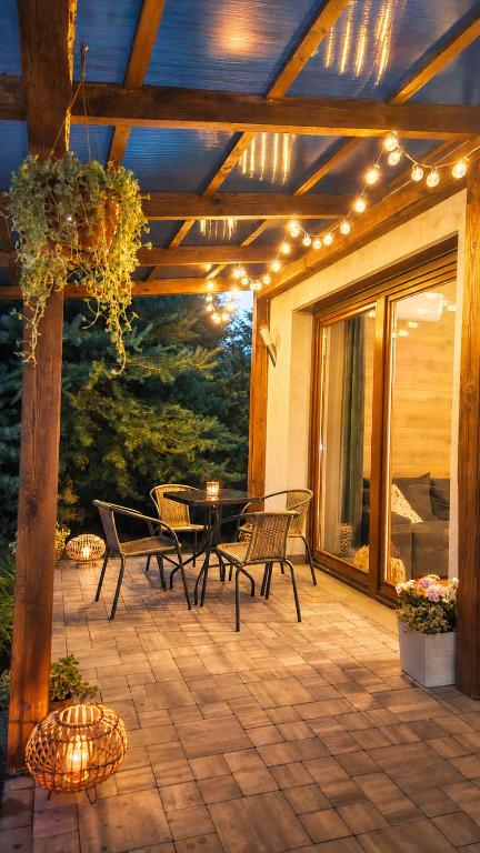 a patio with chairs and a table with lights at Sosnowa Kępa in Żdżar
