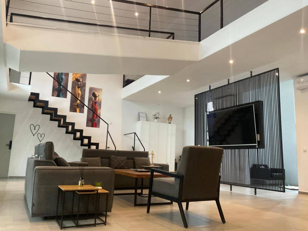 a living room with a tv and a couch and chairs at Mais Residence in Bijilo