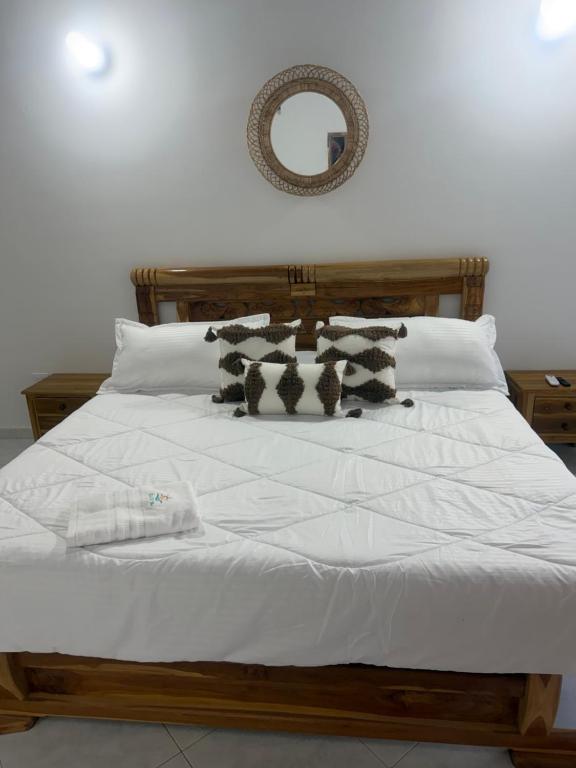 a bed with white sheets and black and white pillows at Cabaña Sueños del Mar in Santa Marta