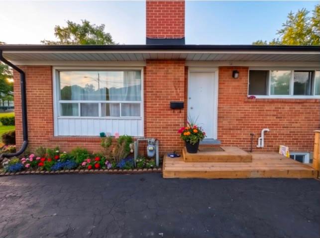 a brick house with a porch with a wooden deck at Treverton Retreat in Toronto