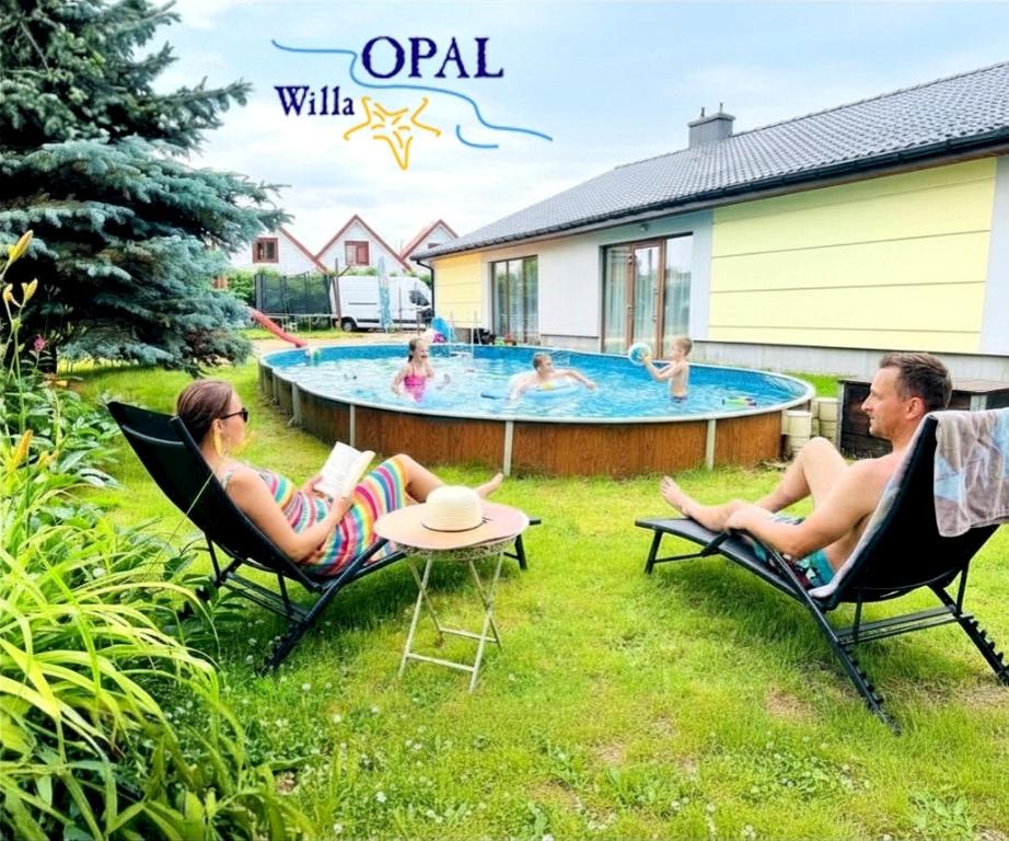 a man and a woman sitting in chairs by a pool at Willa Opal , 250 m do morza in Grzybowo