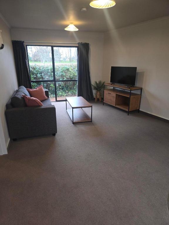 a living room with a couch and a flat screen tv at Raceway Lodge in Feilding