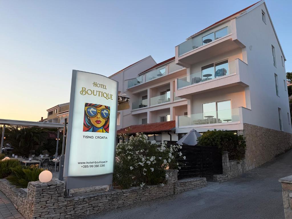 a sign in front of a building with a building at Hotel BOUTIQUE in Tisno