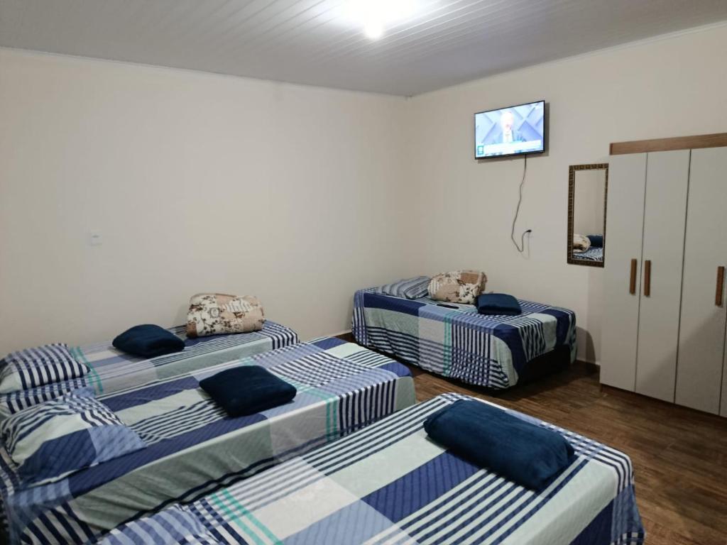 a room with three beds in a room at Pousada Paraíso in Telêmaco Borba
