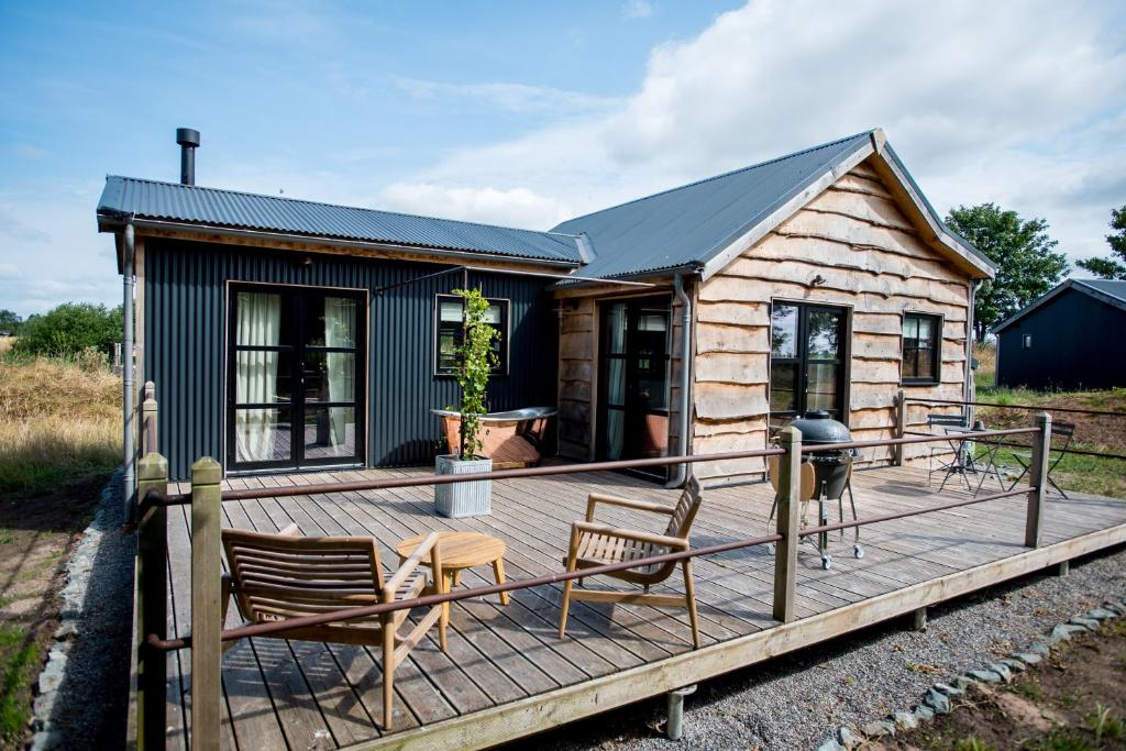 a cabin with a deck with chairs and a grill at Clover in Wrenbury