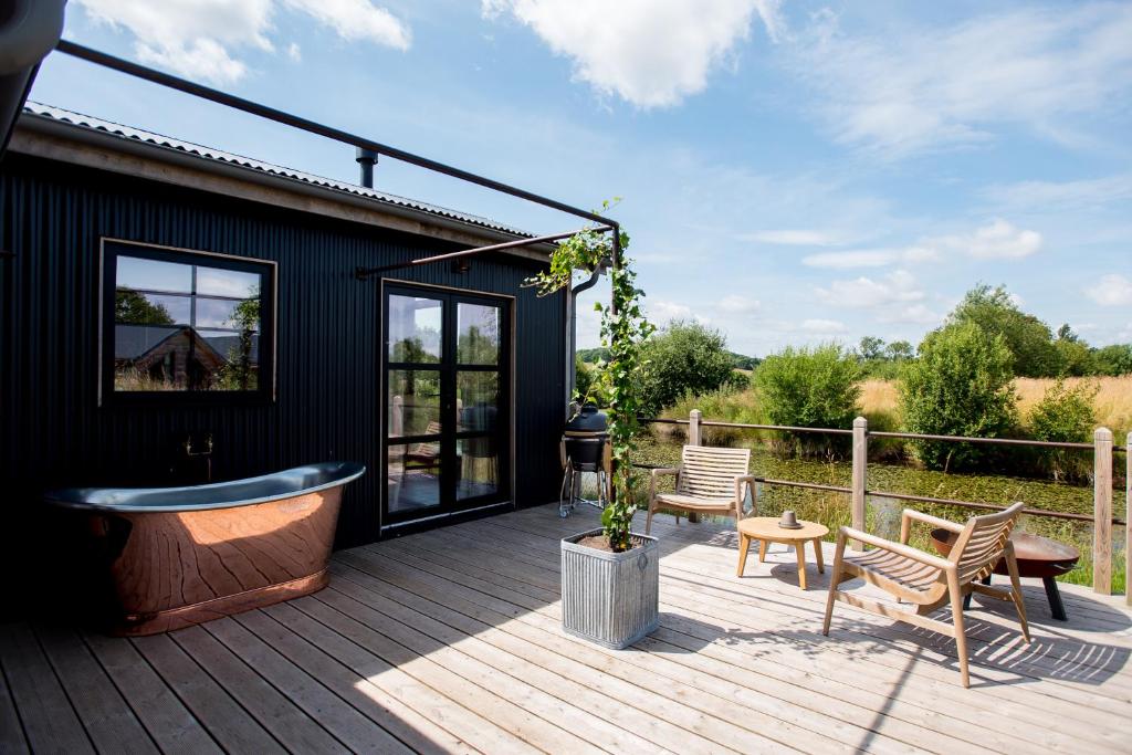 a deck with a tub and chairs on a house at Iris - The Nook Lodges in Nantwich