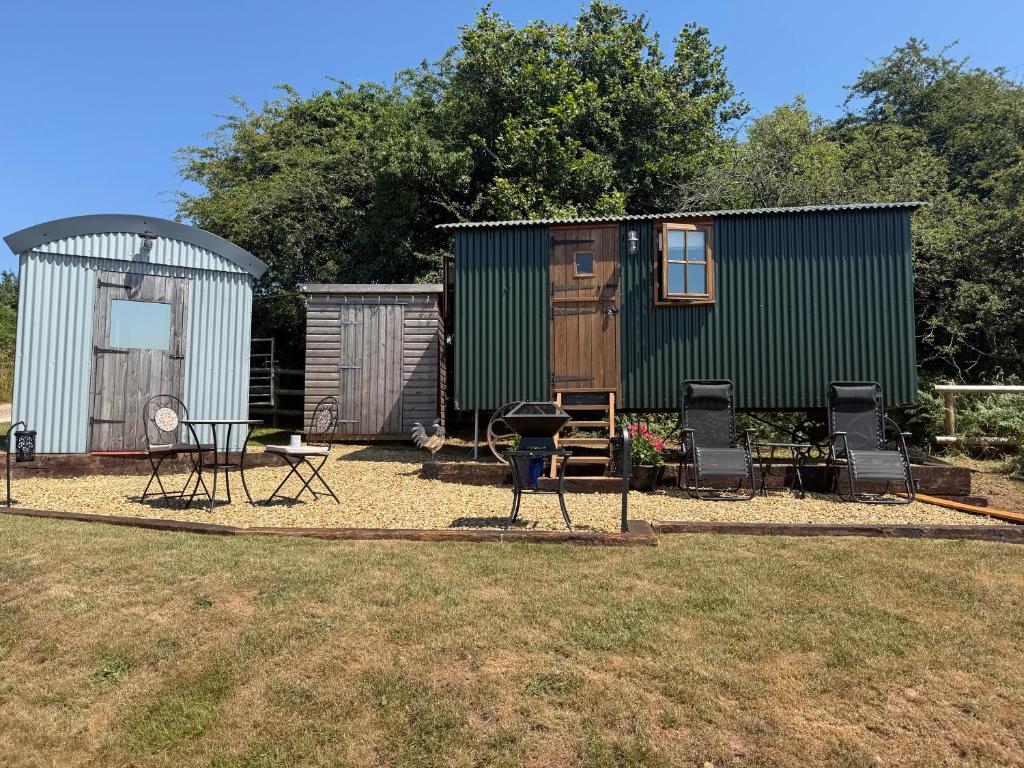 a tiny house with chairs and a table and a shed at The Drey in Trelleck