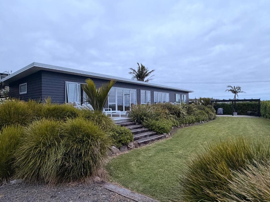 a house with a lawn in front of it at Black Box Bach in Coopers Beach