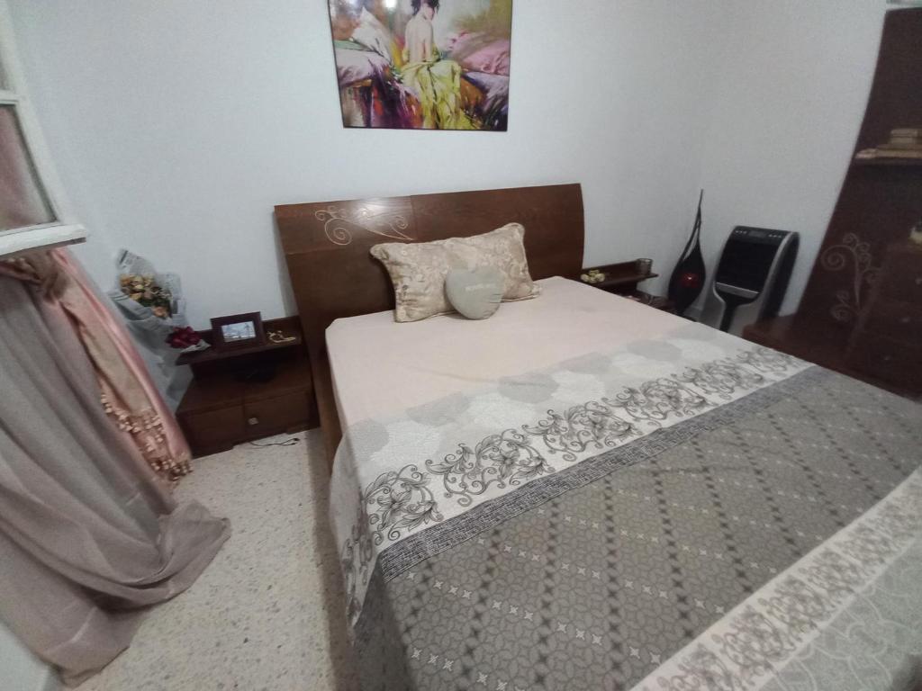 a bedroom with a bed with a wooden headboard at Nour 2 in Le Bardo