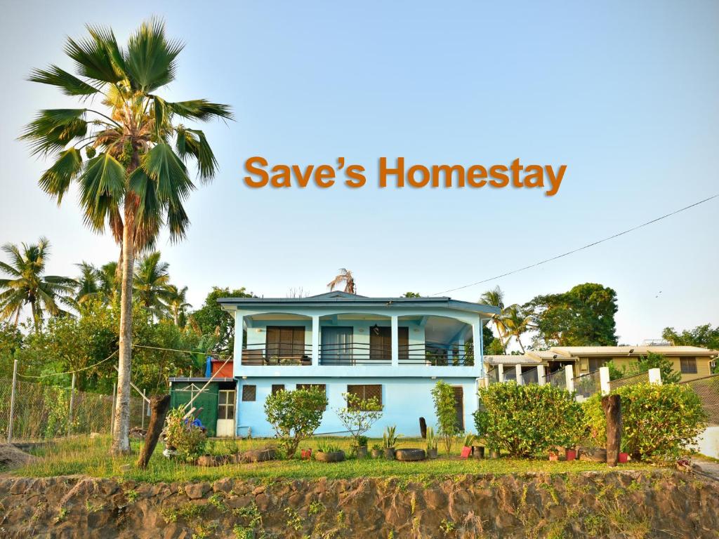 a blue house on a hill with a palm tree at Save's Homestay in Nadi
