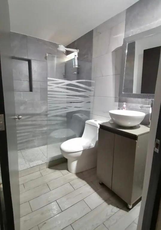 a bathroom with a white toilet and a sink at Casita Verde in Mazatlán