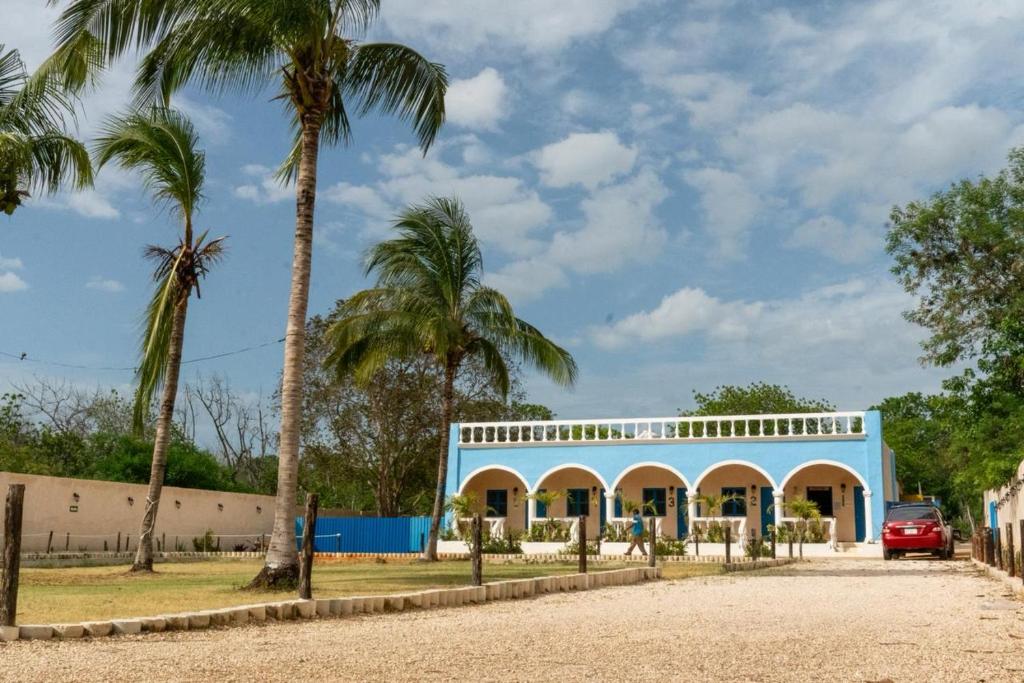 a blue building with palm trees in front of it at Hotel Hacienda IMI 3 in Imí