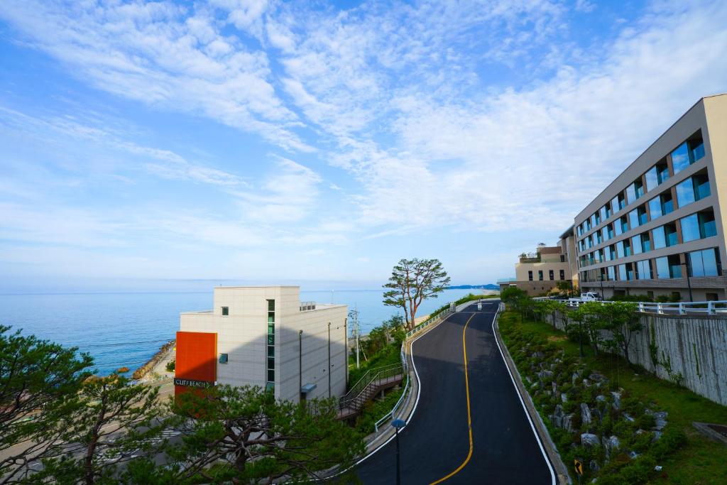 a road next to a building next to the ocean at 클리프비치 in Sangun-ni