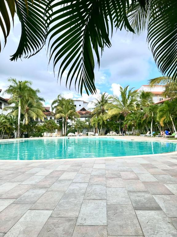 a swimming pool with palm trees in the background at Paraiso Destiny E2 in Bayahibe