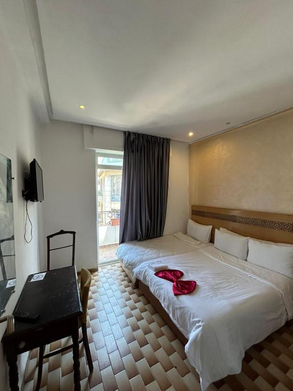 a bedroom with a large bed with a red ribbon on it at Hotel Astoria Tanger in Tangier