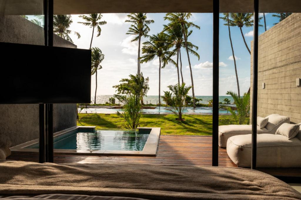 a bedroom with a bed and a view of the ocean at Kamai Pousada Boutique in Pôrto de Pedras