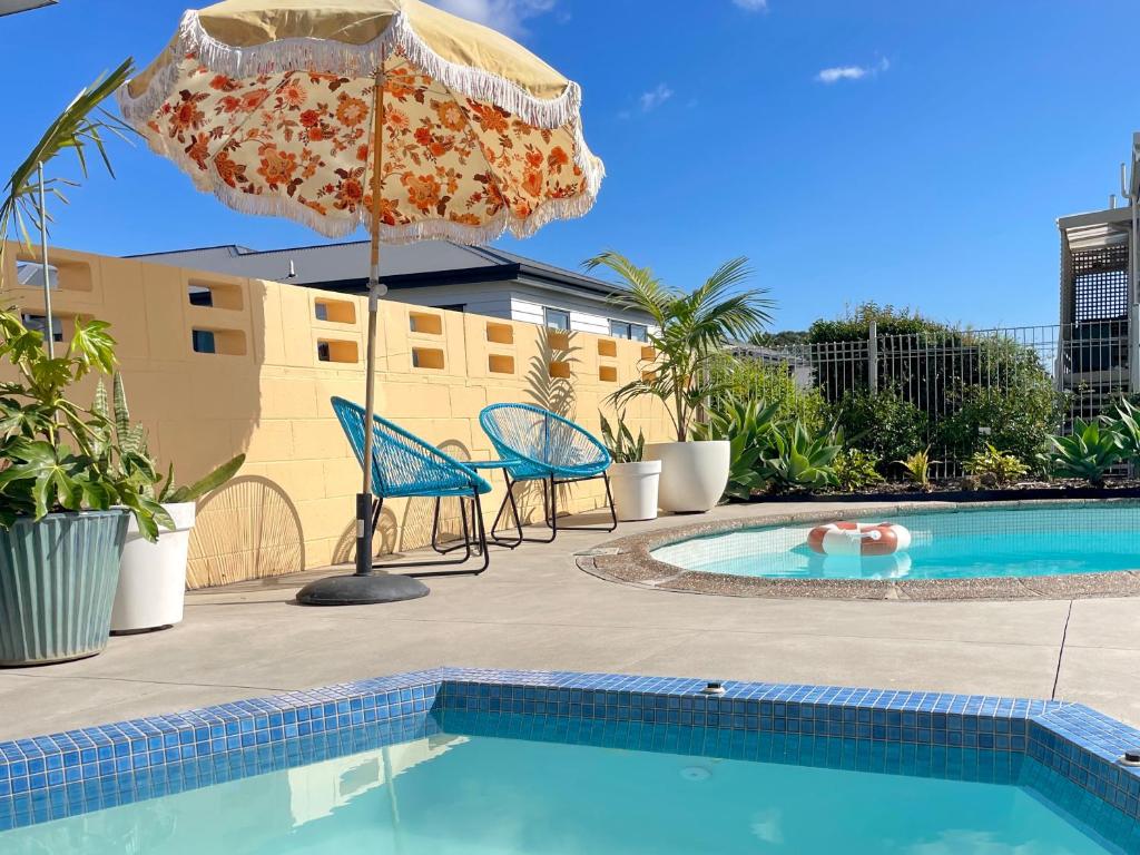 a patio with a pool and an umbrella and chairs at Mount Eden Motel in Auckland