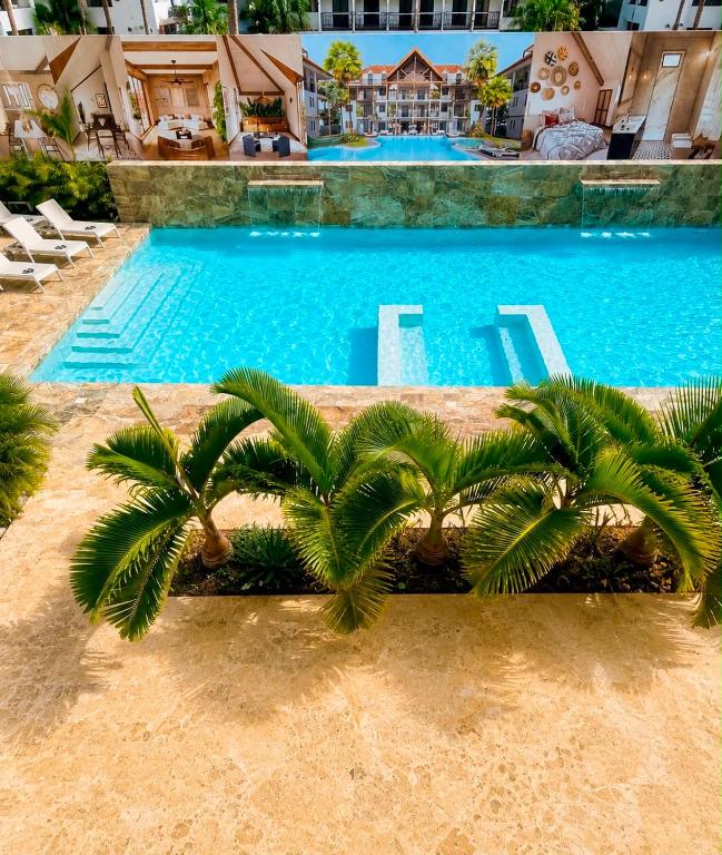 a swimming pool with palm trees in front of a building at Paraiso Destiny Duplex in Bayahibe