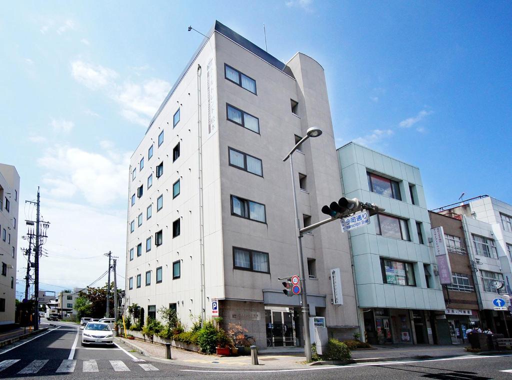 a tall white building on a city street with a traffic light at Hotel Trend Matsumoto in Matsumoto