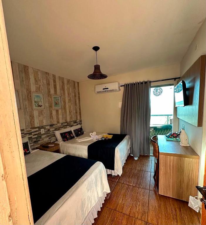 a hotel room with two beds and a television at Pousada Luz Do Sol in Porto Seguro