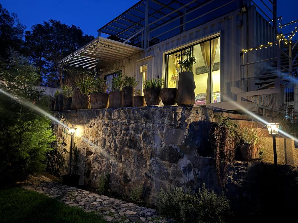 Ein Haus mit Topfpflanzen auf einer Steinmauer bei Nacht in der Unterkunft Pinecone box in Mazamitla