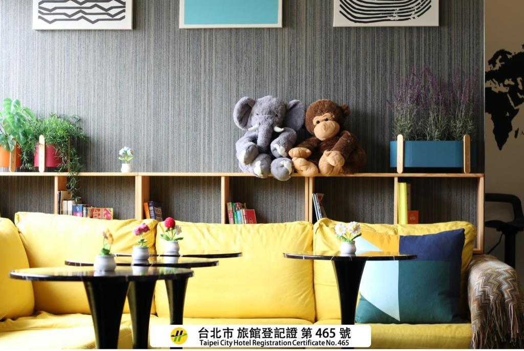 a yellow couch with stuffed animals on a shelf at Easymind Guesthouse Taipei Main Station in Taipei