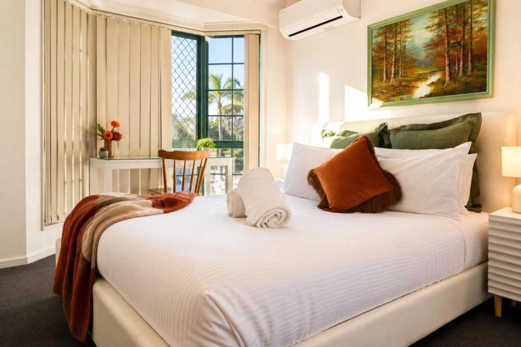 a bedroom with a large white bed with a window at 2BR Retro Luxe Family Hideaway in Gold Coast