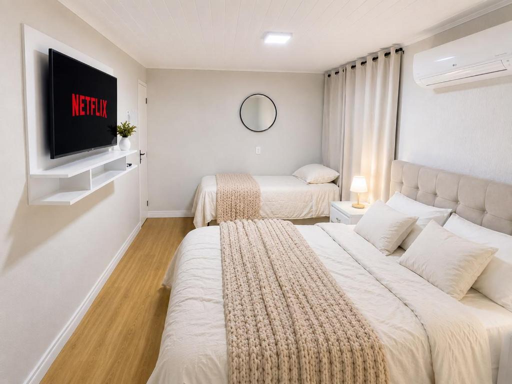 a hotel room with two beds and a tv at Quarto Privativo Próximo à BR in São José