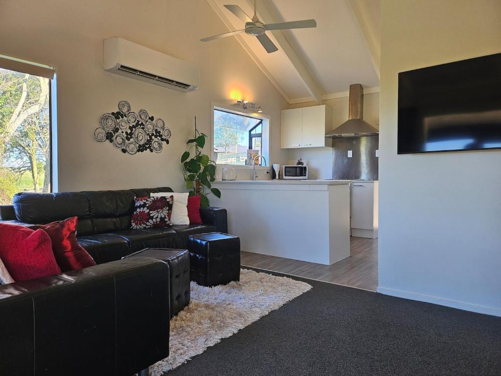 a living room with a couch and a kitchen at Rolling Hills Cottage in Tauwhare