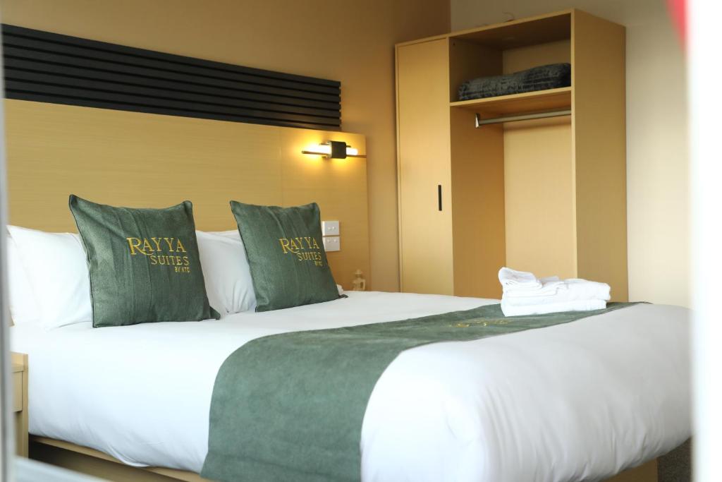 a bedroom with a large bed with green pillows at Rayya Suites , Invercargill in Invercargill